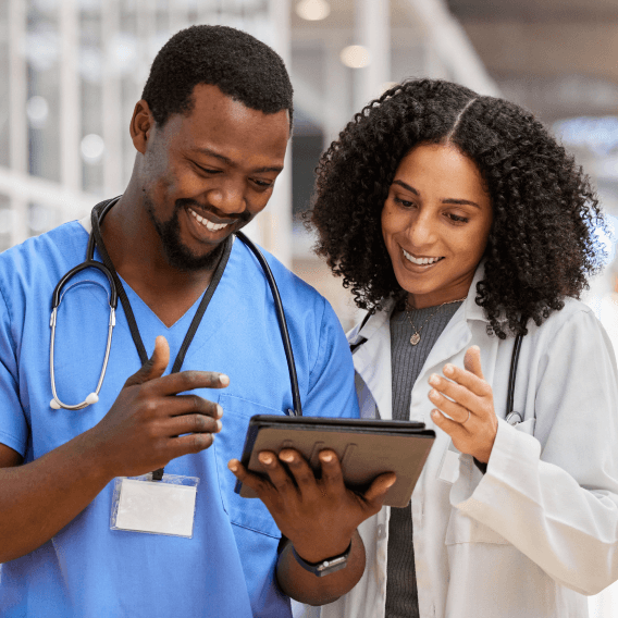 Two doctors smiling and looking at a tablet